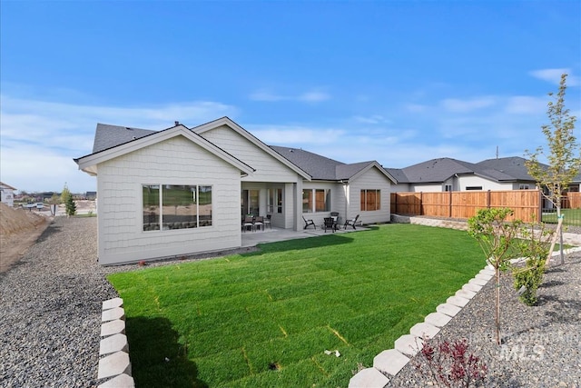 rear view of house with a patio area, fence, and a yard