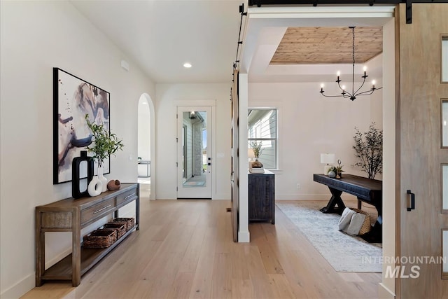 foyer entrance with arched walkways, recessed lighting, a barn door, light wood-style floors, and baseboards