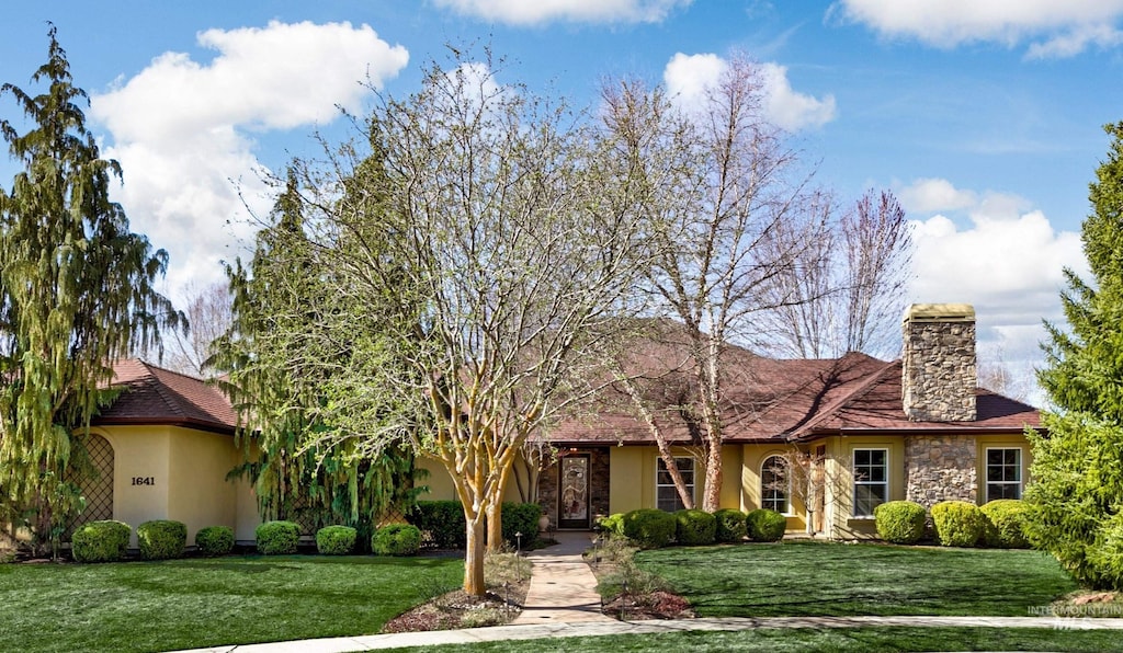 1641 N Kenwood Pl, Eagle, ID 83616 - view of front of house featuring stucco siding, a front lawn, stone siding, and a chimney