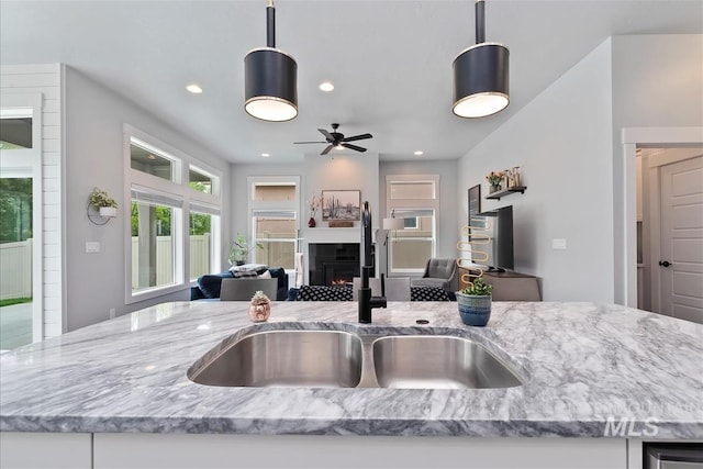 3090 NW 13th St, Meridian, ID 83646 - kitchen featuring a sink, light stone counters, a warm lit fireplace, open floor plan, and recessed lighting