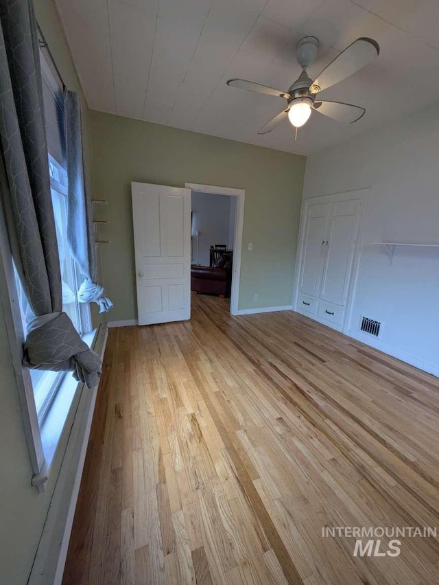 unfurnished bedroom featuring a ceiling fan, light wood-type flooring, visible vents, and baseboards