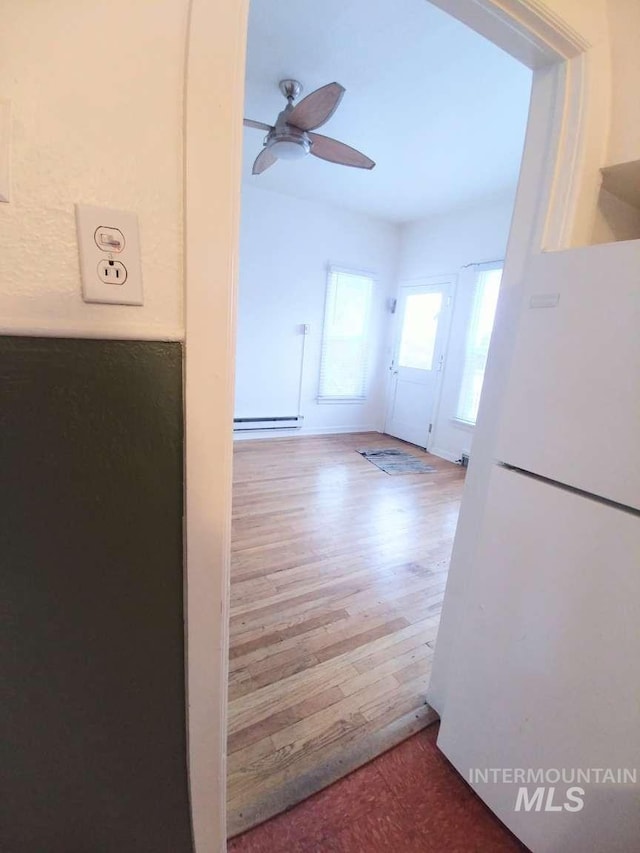 interior space featuring a baseboard heating unit, ceiling fan, and wood finished floors