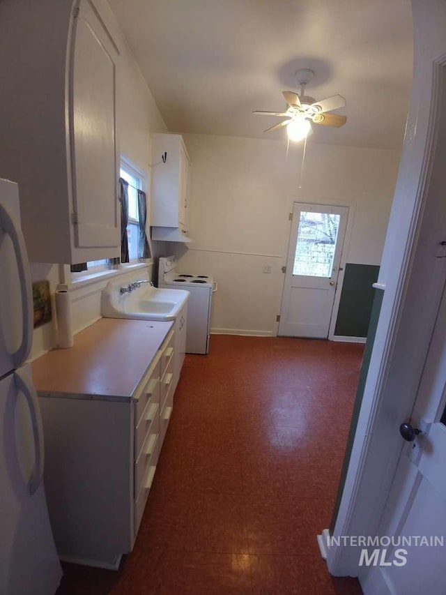 kitchen featuring a sink, white cabinetry, light countertops, tile patterned floors, and washer / dryer