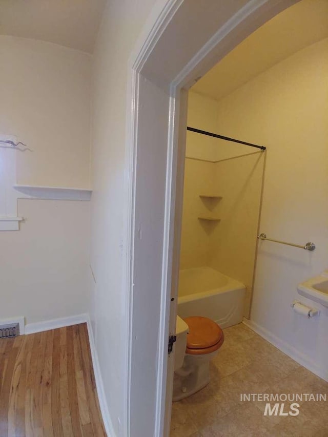 bathroom featuring toilet, baseboards, bathtub / shower combination, and visible vents