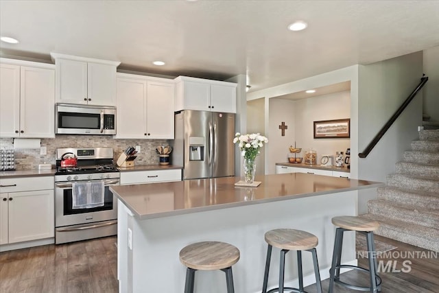 12131 W Precept Ln, Kuna, ID 83634 - kitchen with appliances with stainless steel finishes, recessed lighting, a breakfast bar area, wood finished floors, and white cabinets