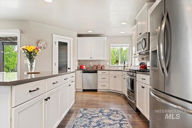 12131 W Precept Ln, Kuna, ID 83634 - kitchen featuring appliances with stainless steel finishes, dark countertops, backsplash, wood finished floors, and white cabinetry