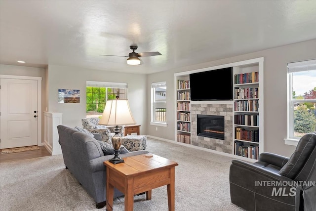 12131 W Precept Ln, Kuna, ID 83634 - carpeted living room featuring a tiled fireplace, ceiling fan, plenty of natural light, and baseboards