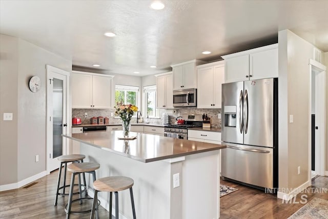 12131 W Precept Ln, Kuna, ID 83634 - kitchen with appliances with stainless steel finishes, a kitchen bar, backsplash, white cabinetry, and recessed lighting
