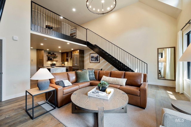 living room featuring a notable chandelier, a towering ceiling, and wood-type flooring