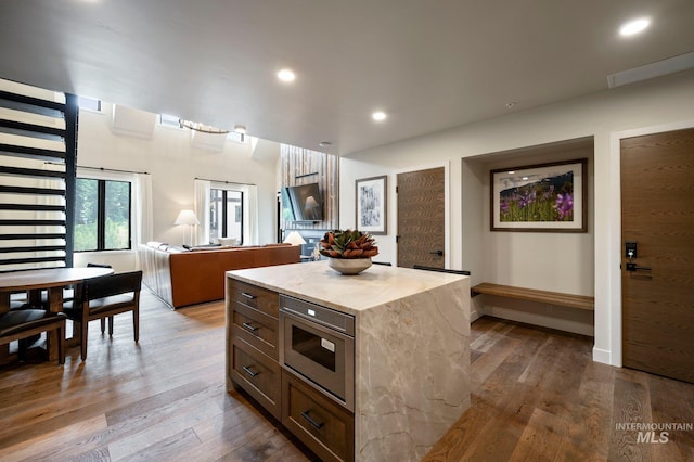 kitchen featuring wood-type flooring, a kitchen island, and stainless steel microwave