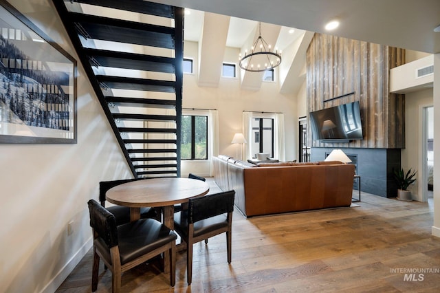 dining area with hardwood / wood-style flooring, an inviting chandelier, and a high ceiling