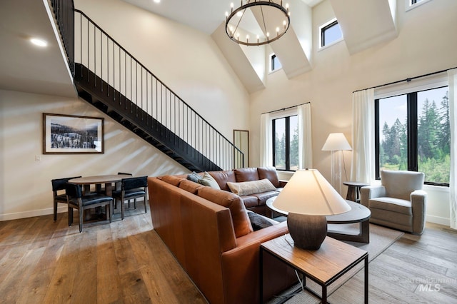 living room featuring a notable chandelier, light hardwood / wood-style flooring, and a high ceiling