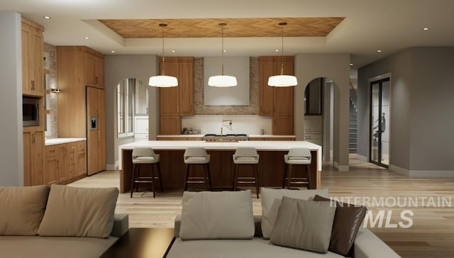1054 N Delehaye Ave, Eagle, ID 83616 - kitchen with arched walkways, a raised ceiling, open floor plan, light countertops, and light wood-type flooring