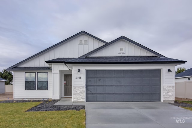 view of front of property featuring roof with shingles, an attached garage, board and batten siding, driveway, and a front lawn