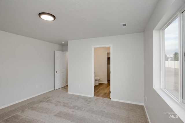 carpeted empty room with a healthy amount of sunlight, visible vents, and baseboards