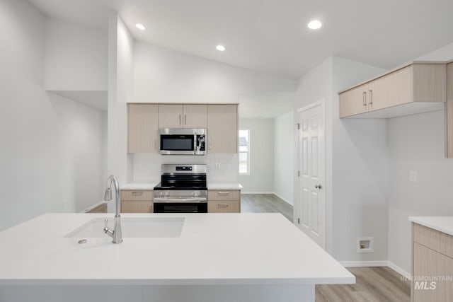 kitchen with lofted ceiling, modern cabinets, stainless steel appliances, and light brown cabinetry