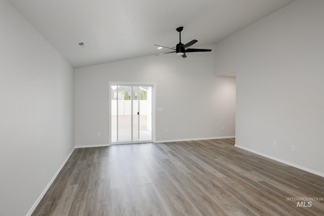 spare room featuring lofted ceiling, visible vents, ceiling fan, wood finished floors, and baseboards