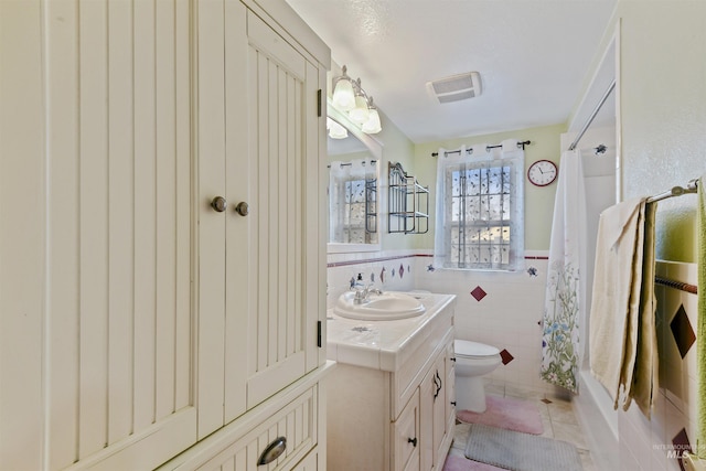 full bathroom featuring vanity, shower / bath combination with curtain, tile patterned flooring, toilet, and tile walls