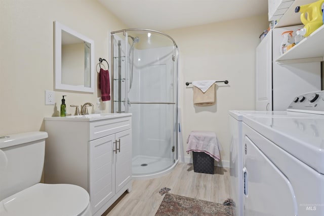 bathroom featuring vanity, separate washer and dryer, hardwood / wood-style flooring, and a shower with door