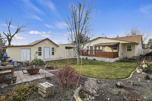 back of house with a deck, an outdoor fire pit, and a lawn