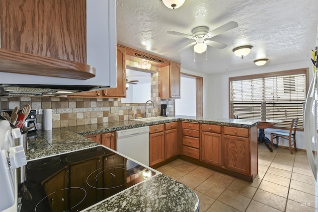 kitchen featuring white dishwasher, sink, decorative backsplash, light tile patterned floors, and kitchen peninsula