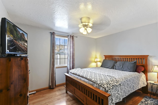 bedroom featuring ceiling fan, light hardwood / wood-style flooring, and a textured ceiling