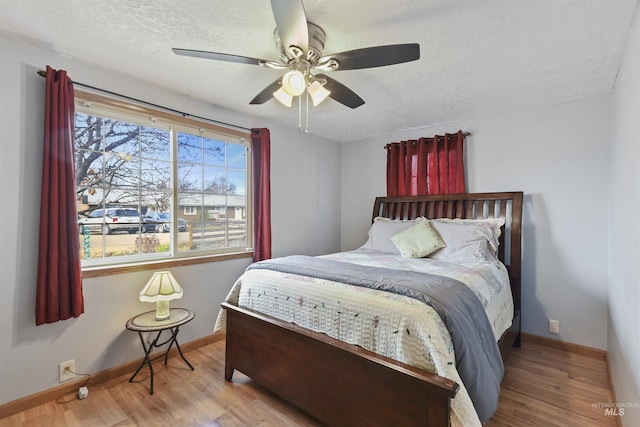 bedroom featuring ceiling fan, light hardwood / wood-style flooring, and a textured ceiling