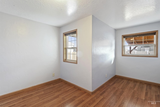 empty room with dark hardwood / wood-style flooring and a textured ceiling