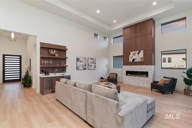 9891 W Napier Ct, Star, ID 83669 - living room with light wood finished floors, a towering ceiling, a tray ceiling, and a large fireplace