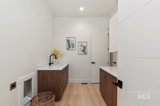 9891 W Napier Ct, Star, ID 83669 - clothes washing area with baseboards, a sink, light wood-style flooring, and recessed lighting