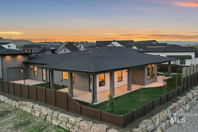 9891 W Napier Ct, Star, ID 83669 - back of property featuring a garage, a fenced backyard, a yard, a patio, and a shingled roof