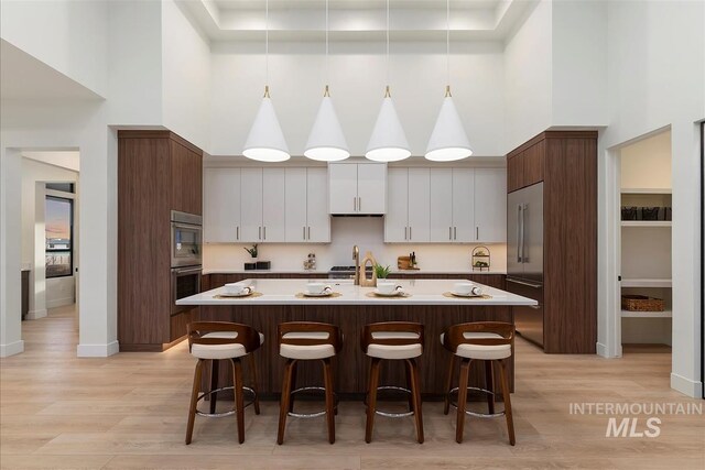 9891 W Napier Ct, Star, ID 83669 - kitchen featuring light wood-style floors, appliances with stainless steel finishes, a high ceiling, and a kitchen breakfast bar