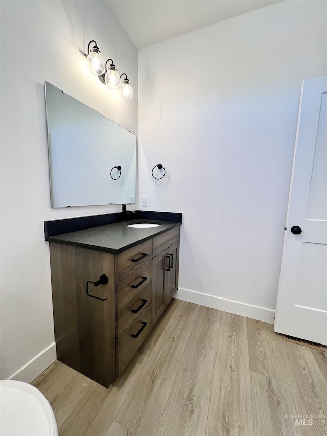 bathroom with toilet, baseboards, wood finished floors, and vanity