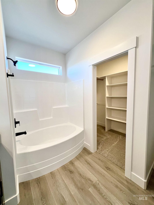 bathroom featuring a spacious closet, wood finished floors, and baseboards