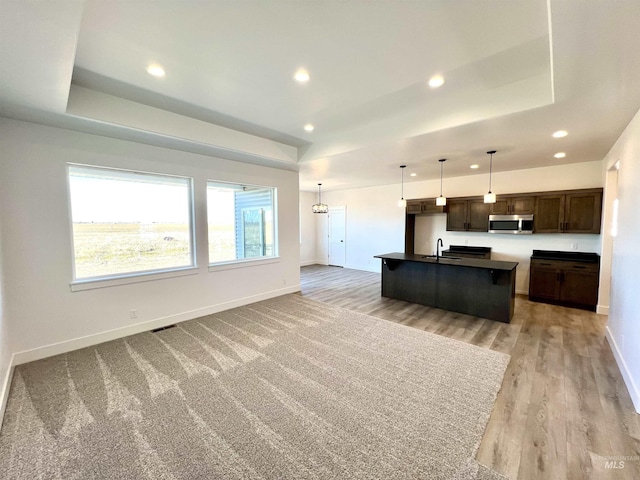 kitchen with a sink, dark countertops, stainless steel microwave, and a tray ceiling