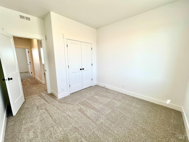 unfurnished bedroom with a closet, carpet flooring, visible vents, and baseboards