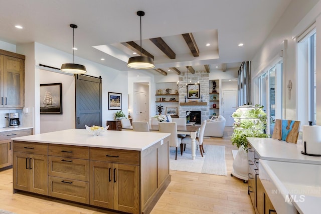 kitchen featuring a fireplace, a barn door, light wood-style flooring, and light countertops