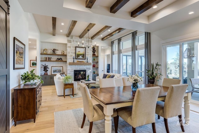 dining space featuring beam ceiling, a stone fireplace, recessed lighting, and light wood-style floors