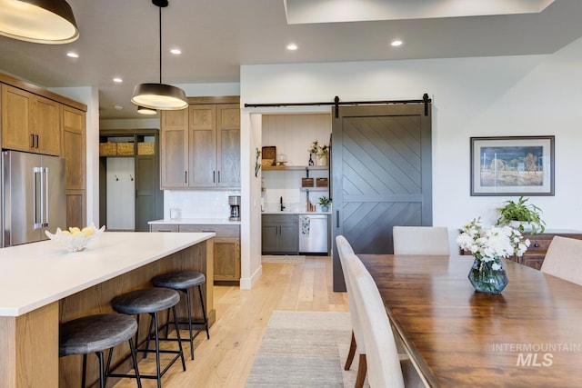 kitchen featuring a center island, a barn door, light wood-style floors, a breakfast bar area, and stainless steel appliances
