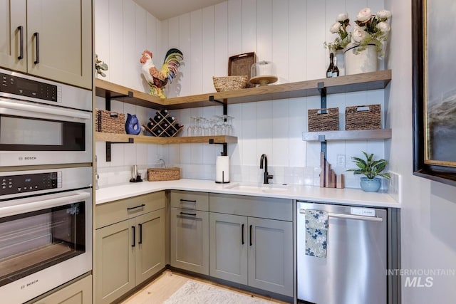 kitchen featuring stainless steel appliances, tasteful backsplash, a sink, and open shelves