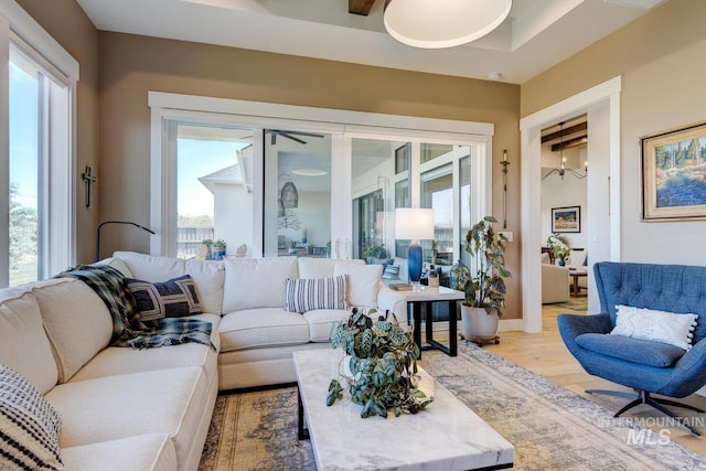 living room with a wealth of natural light, light wood-type flooring, and a ceiling fan