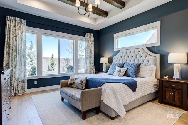 bedroom featuring light wood-style floors, multiple windows, and an inviting chandelier