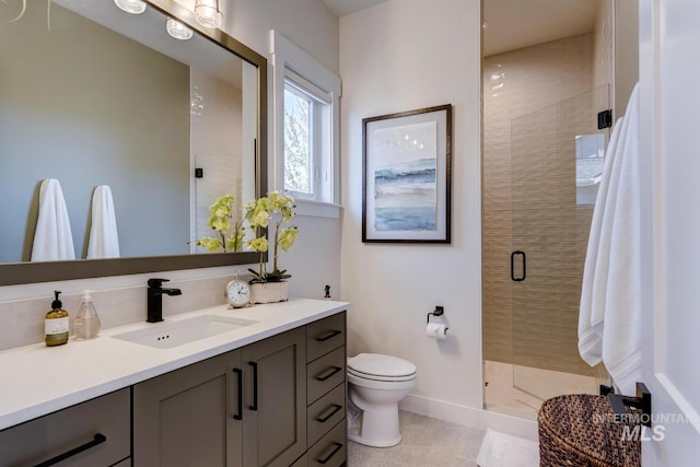bathroom with a shower stall, vanity, baseboards, and toilet