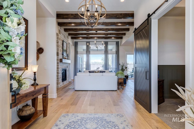 foyer entrance featuring beamed ceiling, light wood-style floors, a notable chandelier, and a barn door