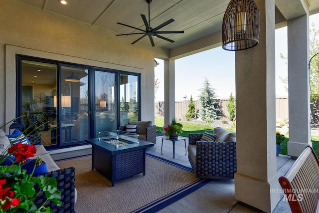 view of patio featuring an outdoor living space with a fire pit, fence, and a ceiling fan