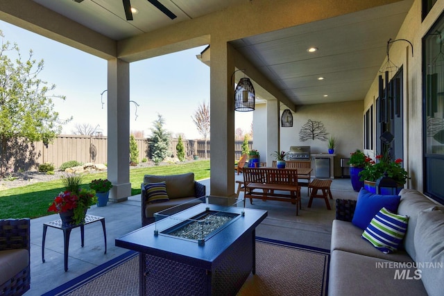view of patio with a grill, fence, an outdoor living space with a fire pit, and ceiling fan