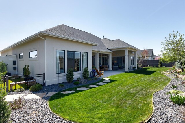 back of property featuring a patio, roof with shingles, stucco siding, fence, and a lawn