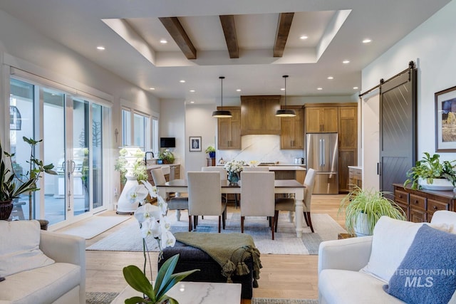 living area with light wood-style flooring, beamed ceiling, recessed lighting, and a barn door