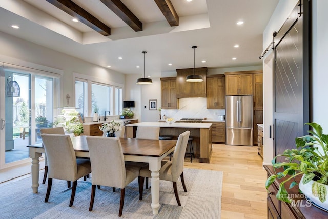 dining room with light wood finished floors, beamed ceiling, recessed lighting, and a barn door