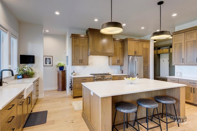 kitchen with custom range hood, a breakfast bar, backsplash, light wood-style floors, and stainless steel appliances